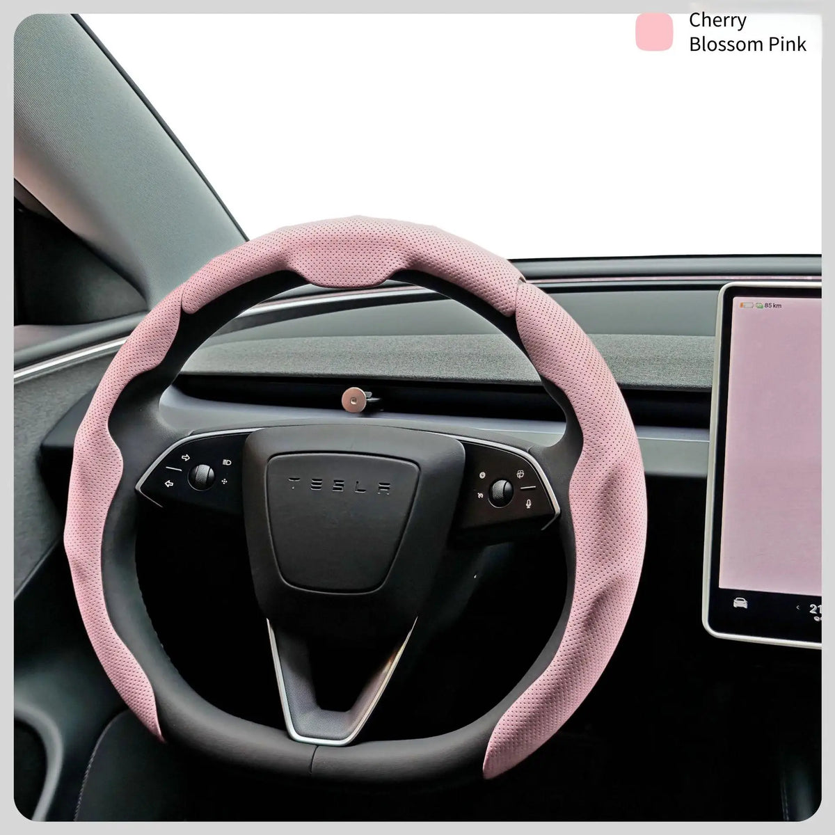 A pink breathable perforated leather steering wheel cover is shown in a car interior with a tablet visible.
