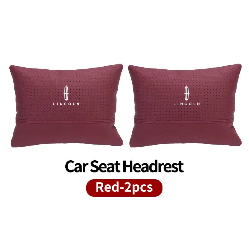 Two maroon Lincoln car seat headrest neck support pillows.