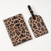 A black and tan leopard print passport holder with card slots attached to a black strap.