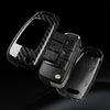 A black premium carbon fiber car key case cover with multiple key slots and a smartphone slot.