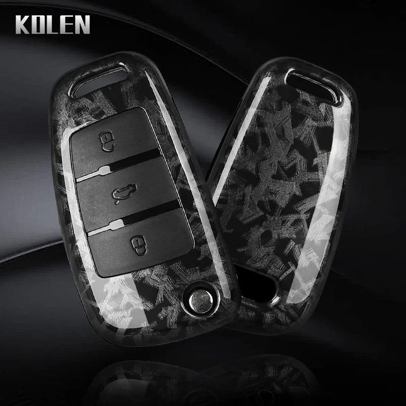 A pair of black carbon fiber car key case covers shown against a dark background.