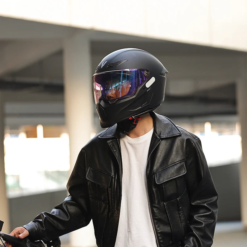 Una persona vistiendo un casco de motocicleta negro y una chaqueta de cuero negra, de pie en el interior.