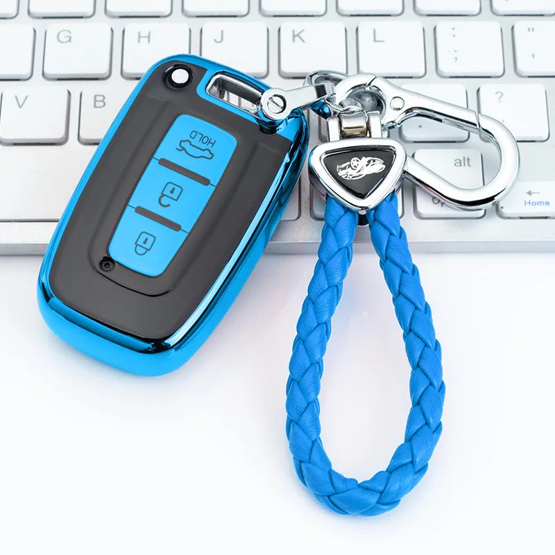 A bright blue universal car key case cover attached to a silver keychain, resting on a white keyboard.