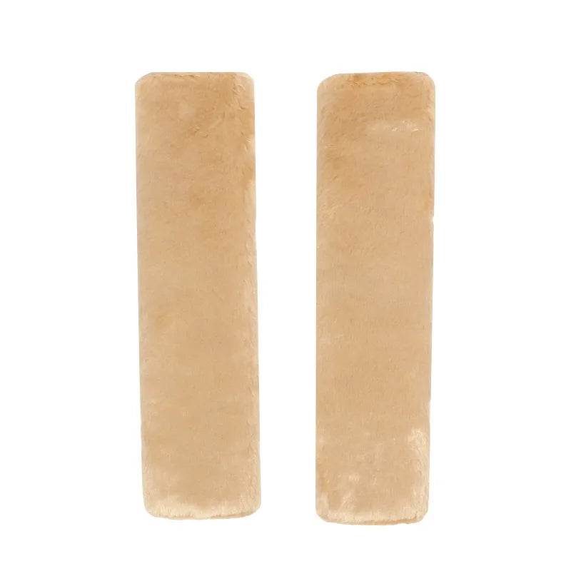 Two beige luxury car seatbelt shoulder pads displayed side by side.