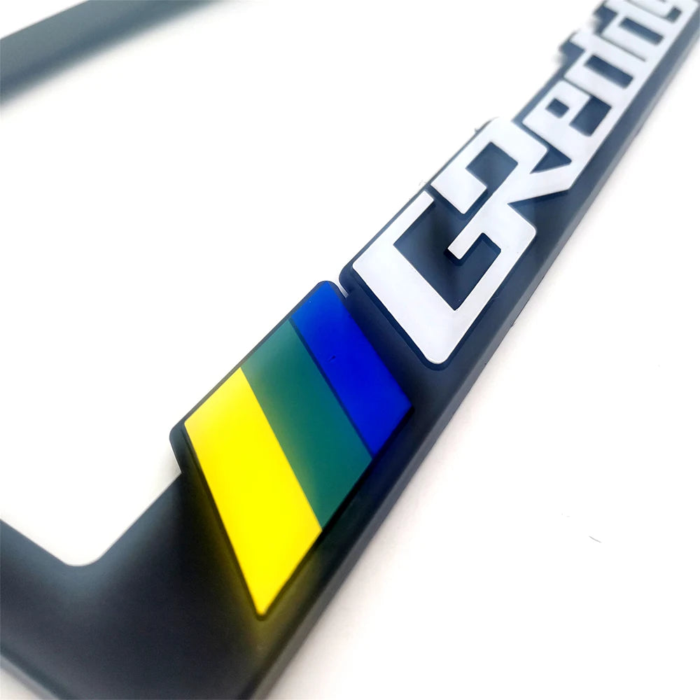 A black license plate frame decoration with a white text design and a blue, yellow, and green colored accent.