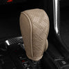 A beige artificial leather handbrake cover is shown resting on a black car interior surface.