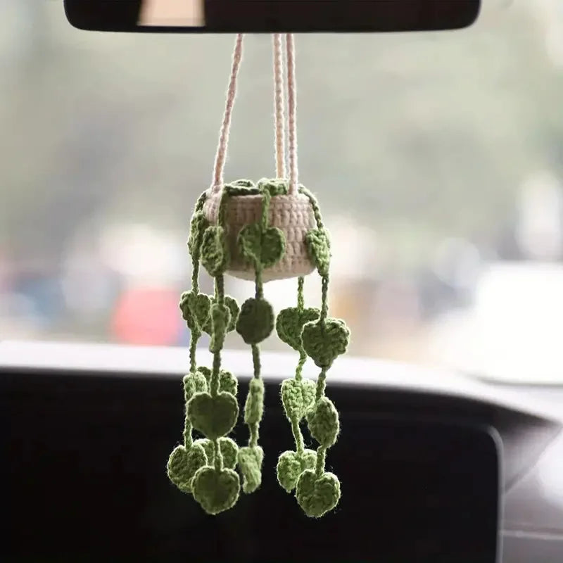 A hanging crochet strawberry decor made of light green yarn with dangling leaves.