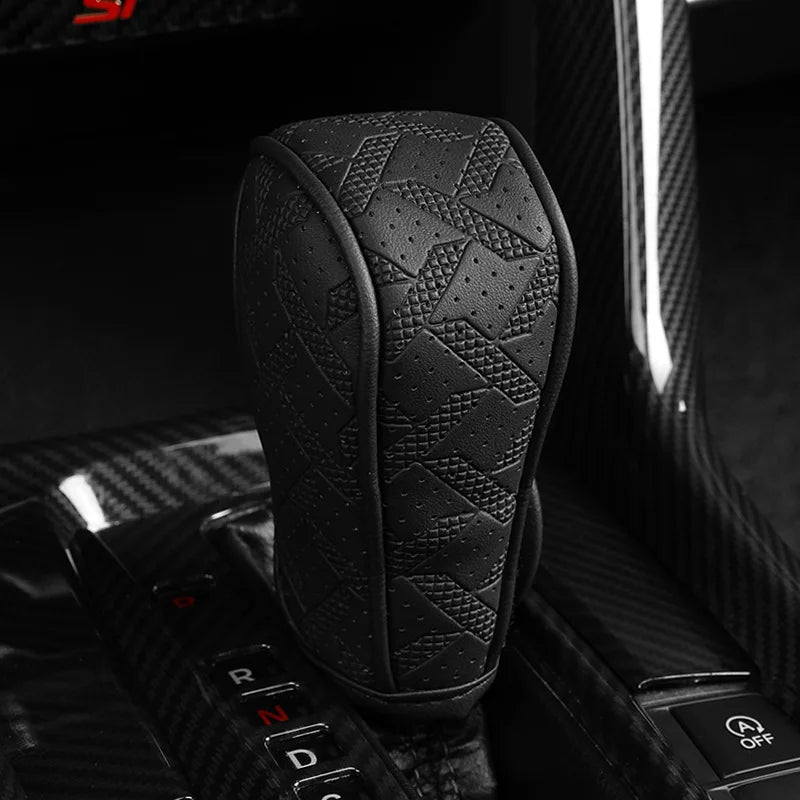 Black artificial leather handbrake cover resting on a car interior control panel.