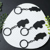 Black alloy car keychains with silver split rings arranged on a white circular background.