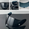 A black motorcycle helmet visor lens is shown in various angles, demonstrating its curved shape and protective design.