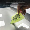 A hand is using a yellow film scraper tool to remove a layer of car film from a surface.