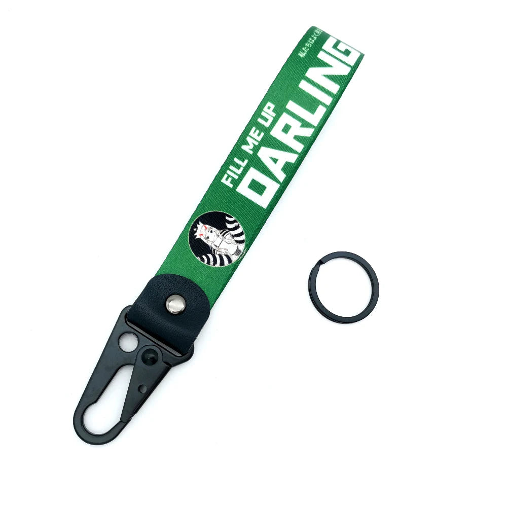 Grüner Lanyard mit weißer Schrift und einem runden Metallring, befestigt an einer schwarzen Clips.