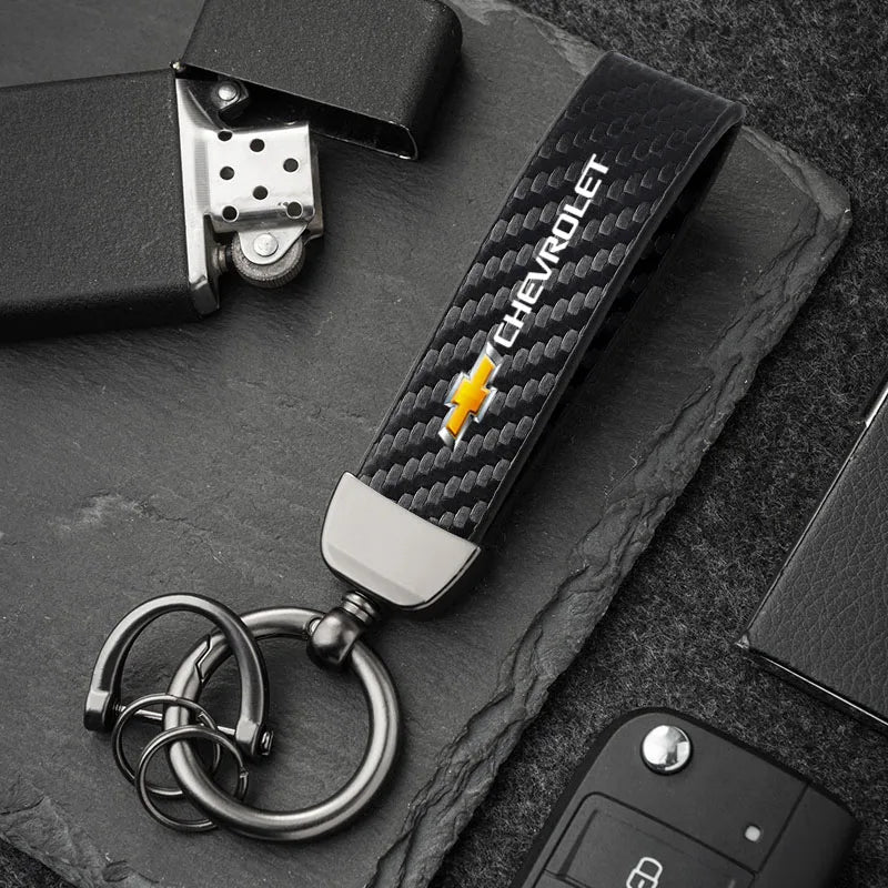 A close-up of a luxury metal Chevrolet key ring set resting on a dark surface.
