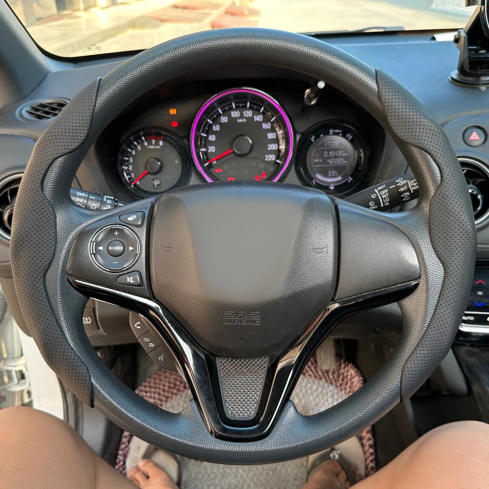 A close-up view of a black steering wheel with a leather-like cover and controls inside a car