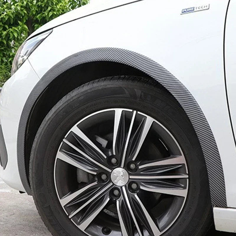Nahaufnahme des Radkastens eines weißen Autos mit schwarzem Kohlefaser-Akzent und Leichtmetallrad.