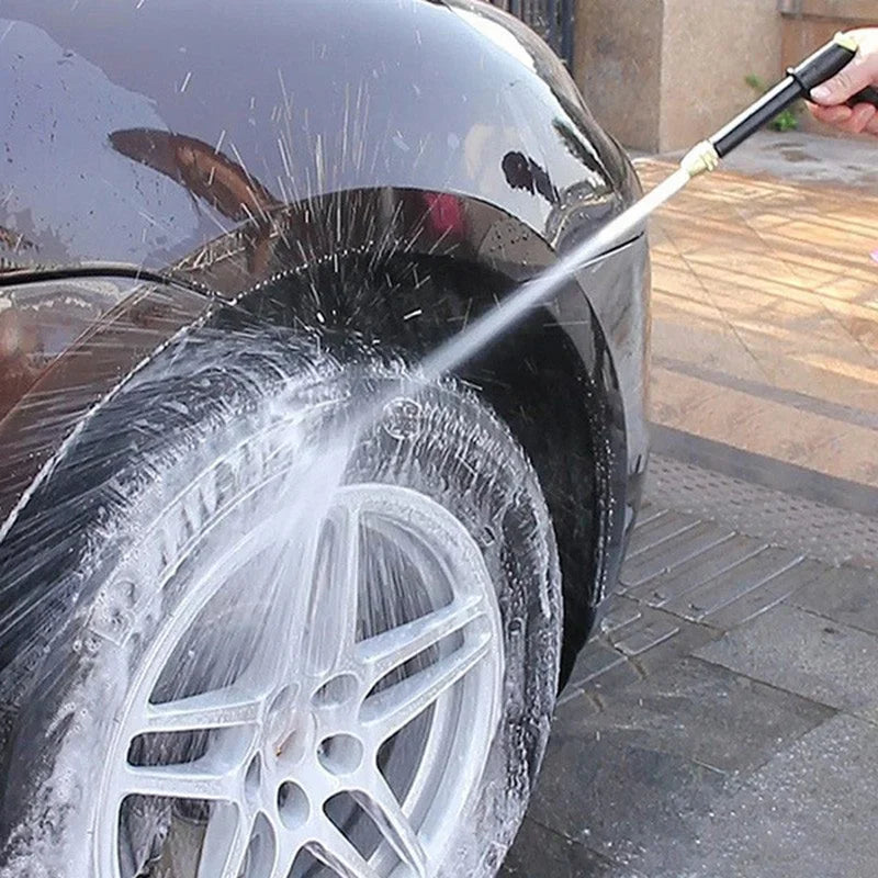A high-pressure water gun sprays water onto a car tire during cleaning or watering.