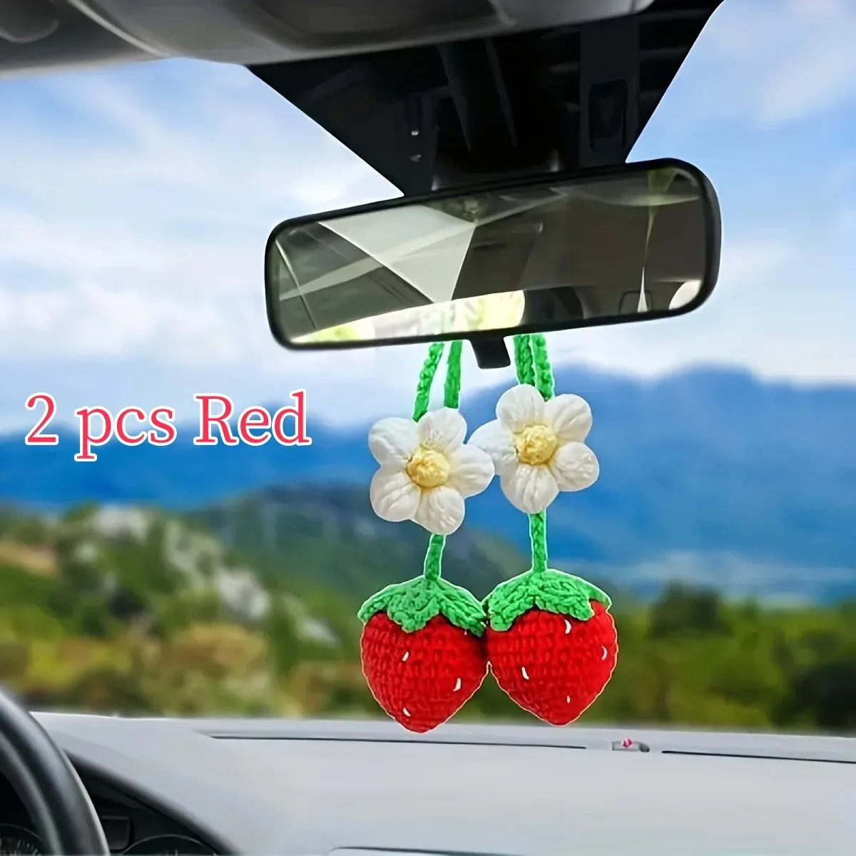 Deux pendentifs en crochet de fraises rouges, clés, accrochés au rétroviseur d'une voiture.