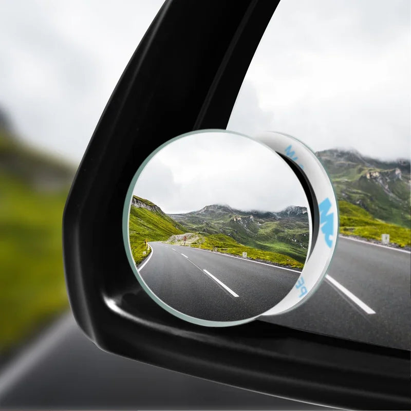 A close-up view of a convex blind spot rearview mirror showing a scenic landscape through the lens.