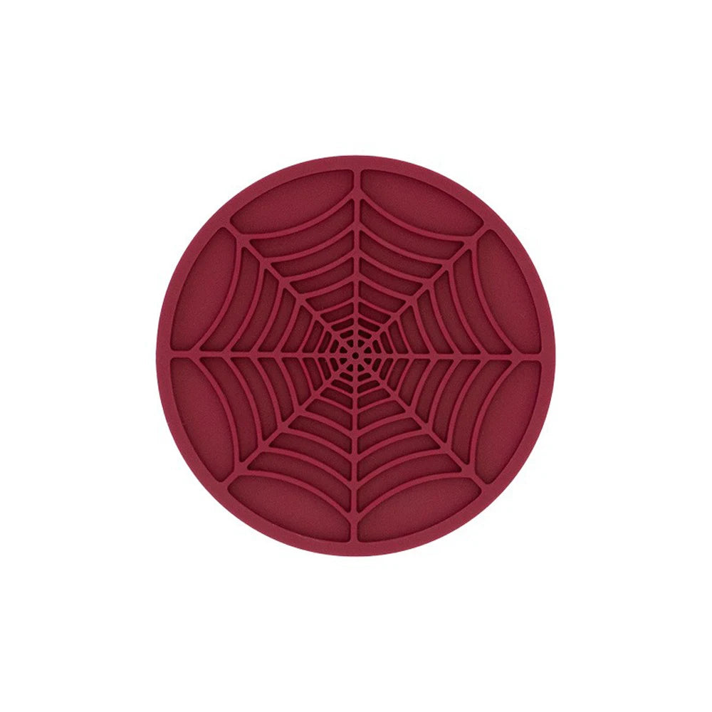 A circular coaster with a detailed, reddish-brown silicone spider web pattern.
