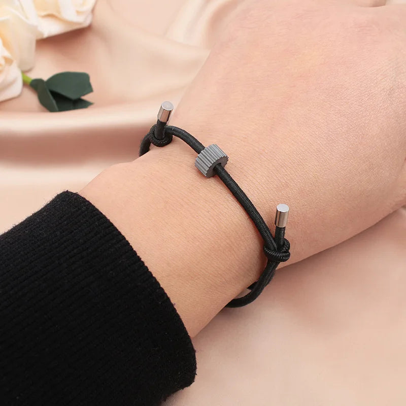 A close-up of a black fitness tracker bracelet on a wrist, resting on a pink fabric.