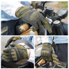 Tactical hard-shell gloves with touchscreen grip shown on a hand gripping a motorcycle handlebar.
