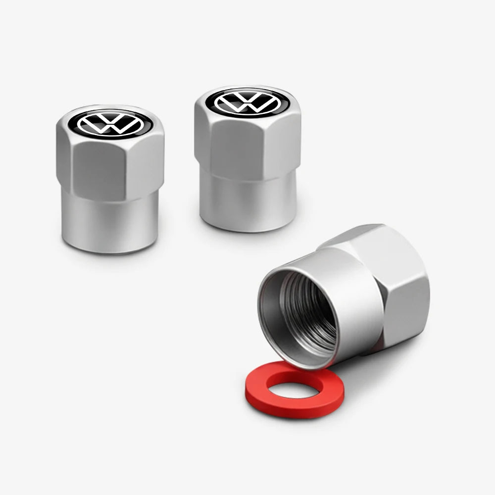 Three silver metal tire valve caps with VW logos and a red rubber ring.
