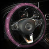 A black steering wheel covered in a sparkly pink rhinestone material.