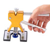 A hand is operating a professional car dent repair puller kit, which is a gold and silver tool used for automotive bodywork.