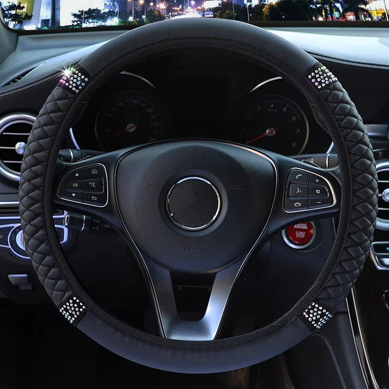 Close-up view of a black leather steering wheel with decorative stitching and controls inside a car
