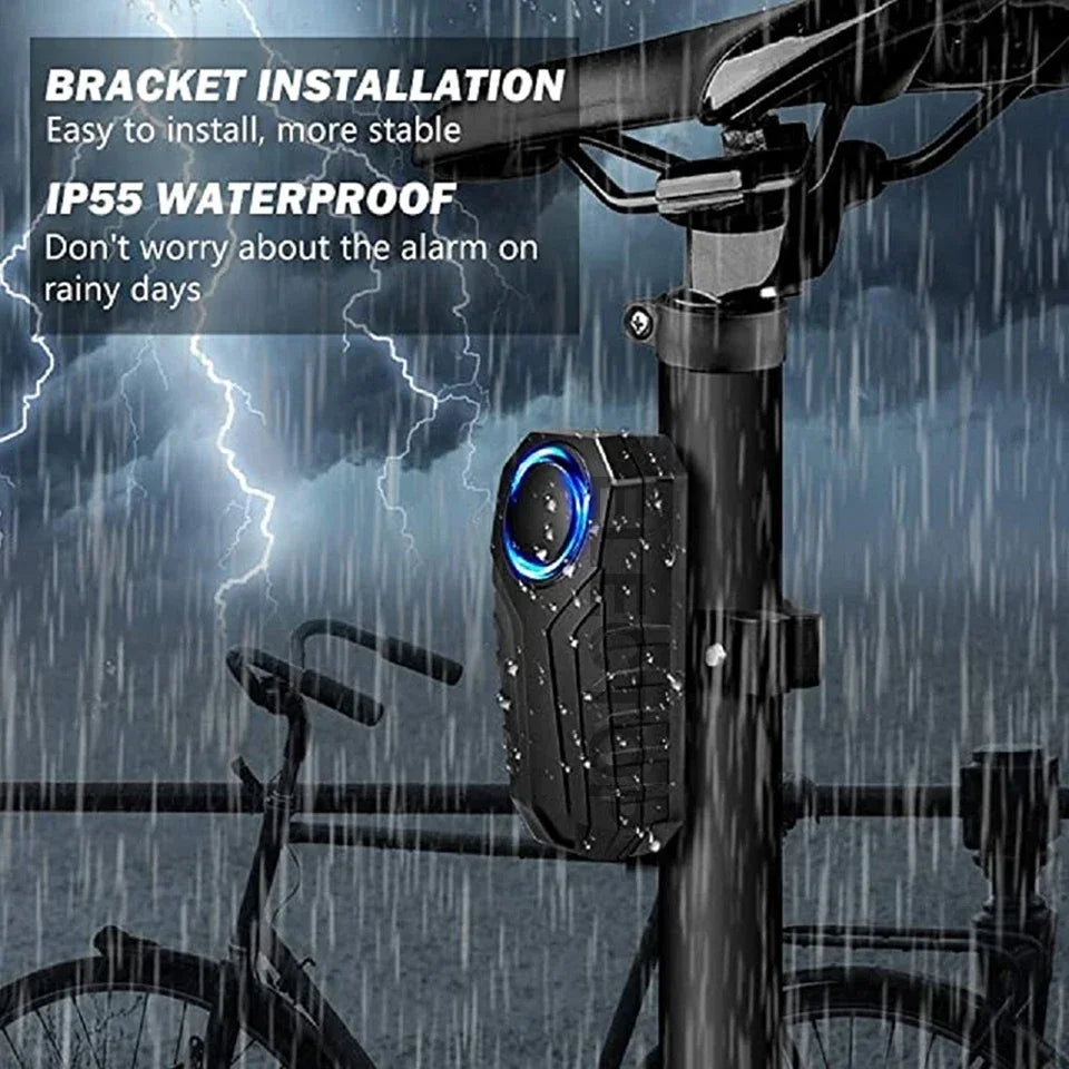 A black wireless bicycle alarm bracket installed on a bike frame, shown in rainy weather context.