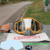 Orange and gray durable motocross and cycling goggles resting on a gray surface.