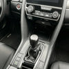 Interior view of a car dashboard showing the gear shift knob and surrounding controls.