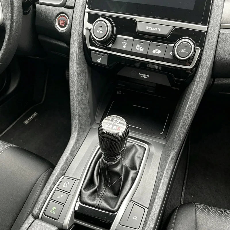 Interior view of a car dashboard showing the gear shift knob and surrounding controls.