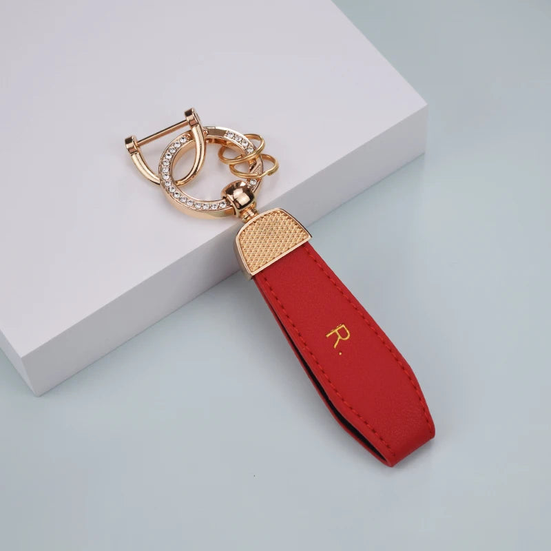 A red TPU car key fob cover with a gold-toned chain and ring attached, resting on a white surface.