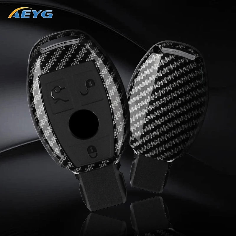 A pair of carbon fiber car key covers for Mercedes models displayed on a dark surface.