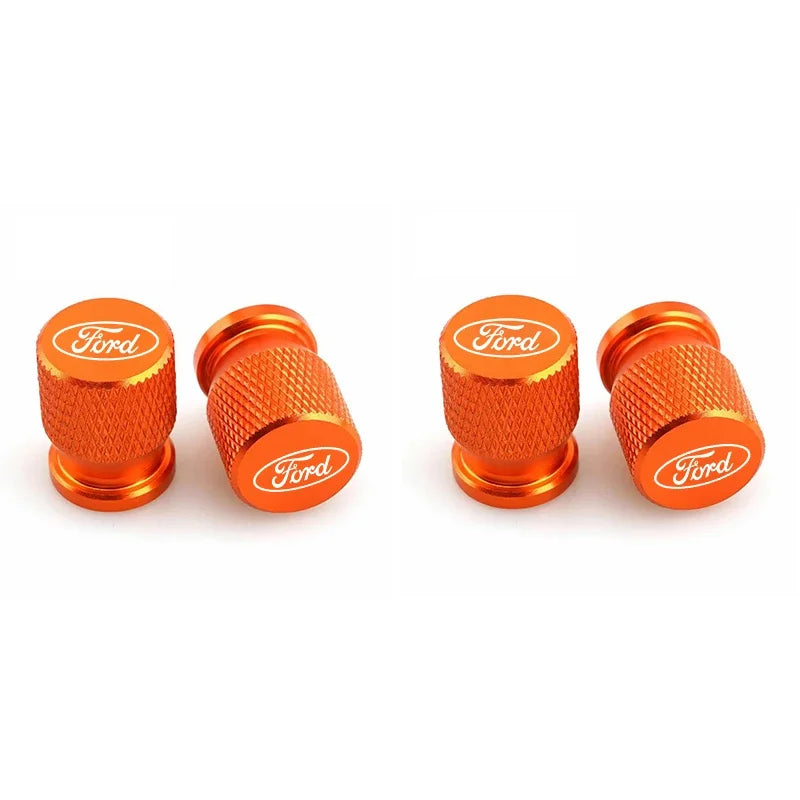 Three orange aluminum Ford car wheel valve caps shown side by side.