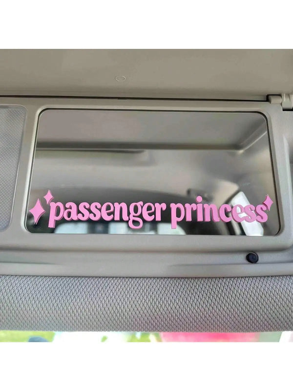 A close-up view of a car sun visor with a pink Passenger Princess decal applied to the interior glass.