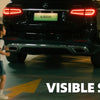 A dark SUV with a visible safety camera mounted on the rear, being approached by children.