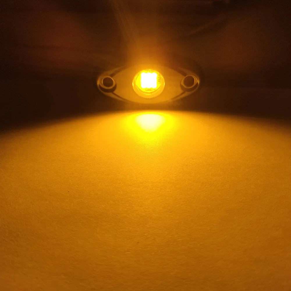 A close-up shot of a bright yellow LED light illuminating a surface, likely an underbody rock light for a vehicle.