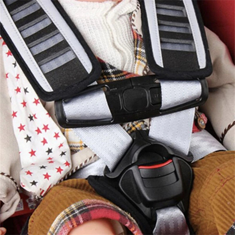 A close-up of a black car seat belt clip for child safety harness attached to a white knitted garment.