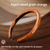 An orange peach wood grain steering wheel cover shown in a close-up view on a wooden surface.