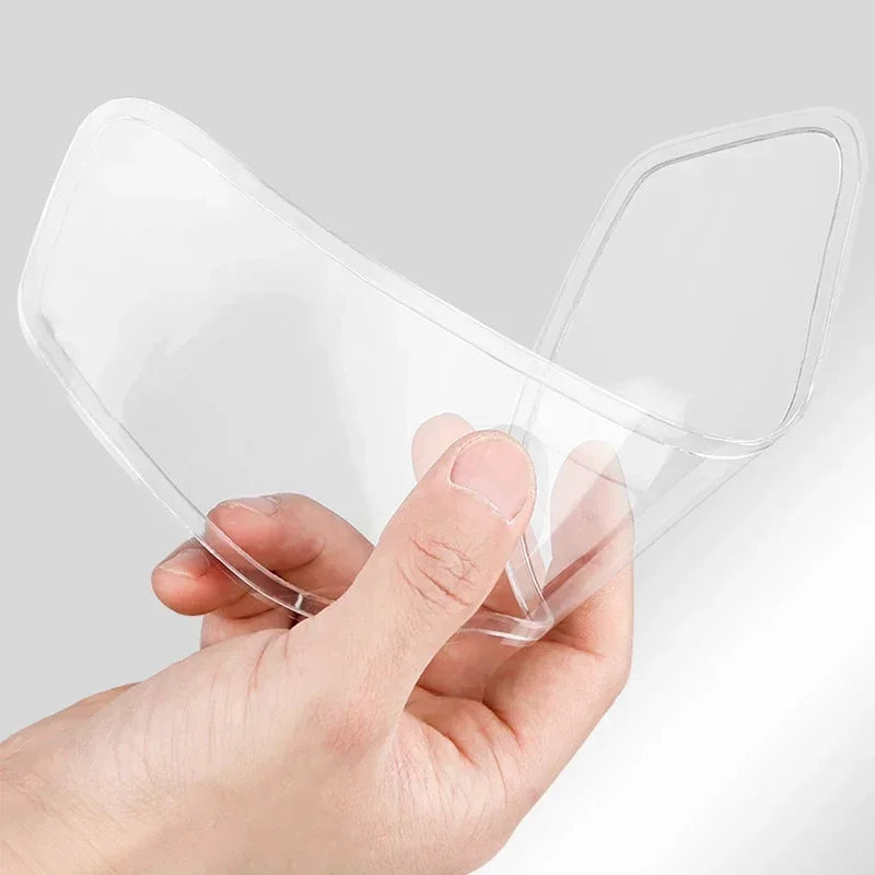 A hand is holding a clear anti-fog and rain-repellent film for a motorcycle helmet visor.