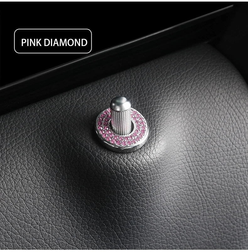 A close-up of a pink diamond car door lock pin trim set featuring a silver and pink gemstone design.