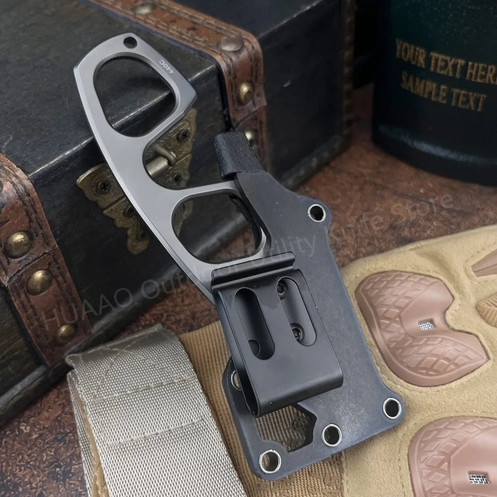 A black fixed blade survival knife with a handle and blade visible, resting on a textured surface.