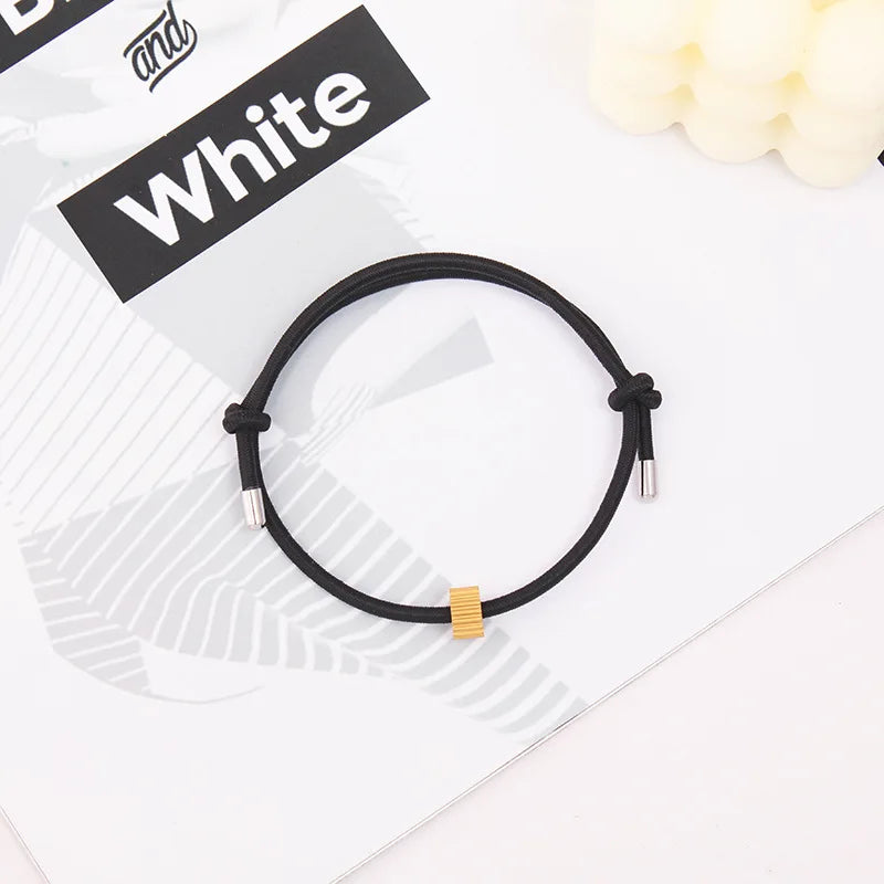 A black heart-shaped fitness tracker bracelet is displayed on a white background next to a sign reading White.