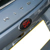 Close-up of a gray Ford vehicle panel showing various emblems and a red Ford badge.