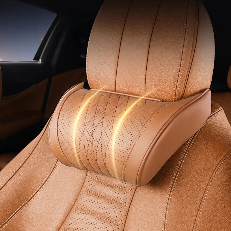 A close-up of a tan leather car neck pillow with stitching and a glowing detail on a car seat.