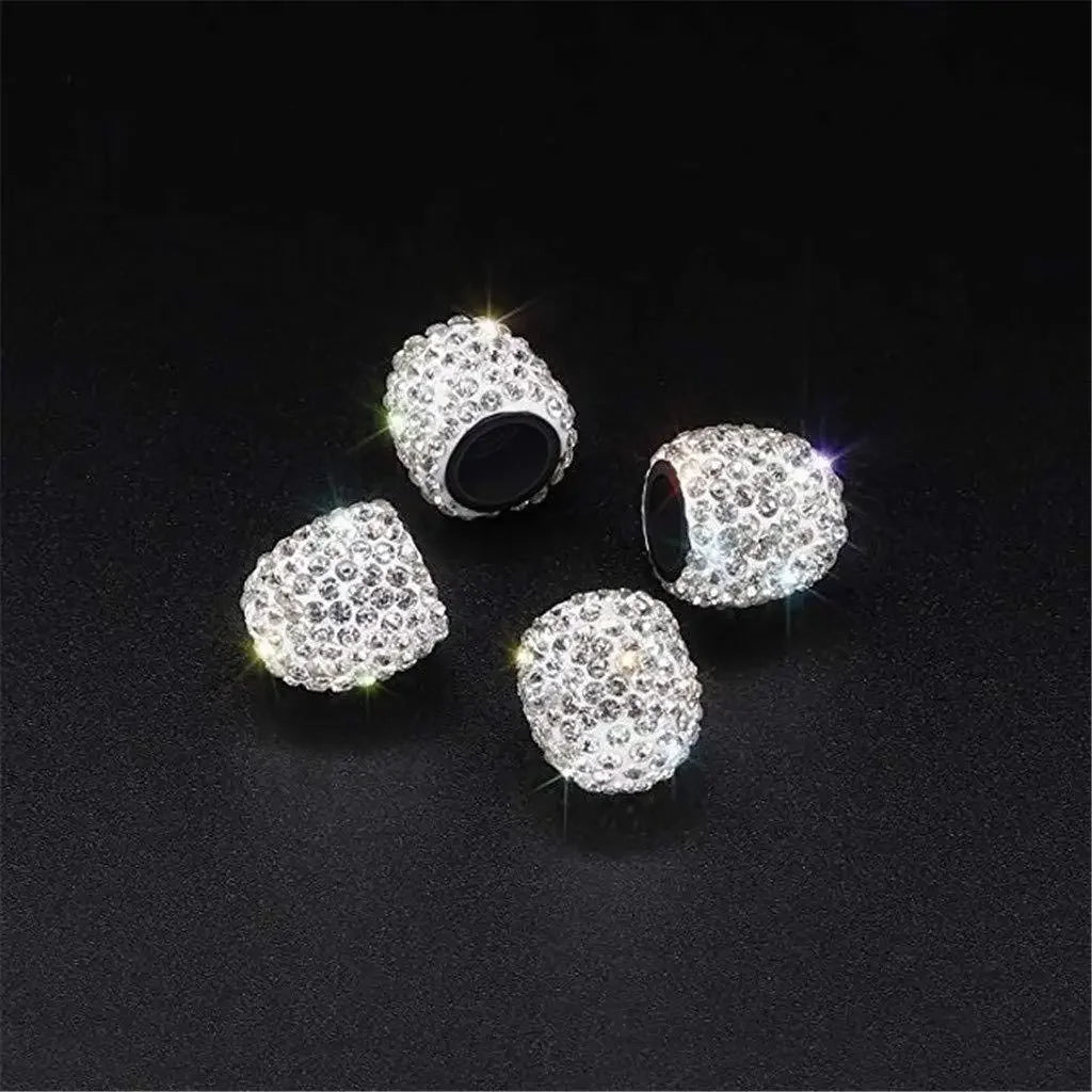 Drei silberne Diamant-verzierte Radventildeckel werden auf einer dunklen Oberfläche präsentiert.