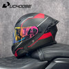 Un casque de moto modulaire noir et rouge DOT est exposé sur un siège en cuir noir.