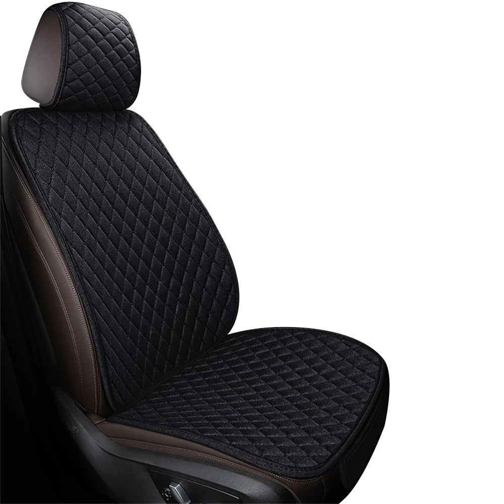 A close-up view of a black upholstered car seat and floor mat with diamond stitching.